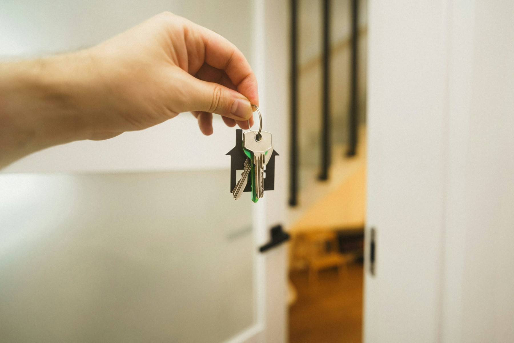 Landlord holding house keys near front door, representing lock change scenario without tenant notification.