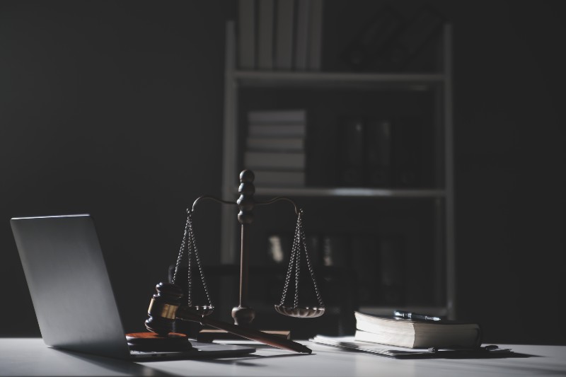 A dark-lit law office scene with a gavel, scale of justice, laptop, and law books, symbolizing legal consultation and decision-making in an immigration case.
