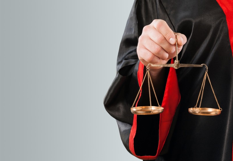 A person in judicial robes holding a balance scale, symbolizing legal fairness