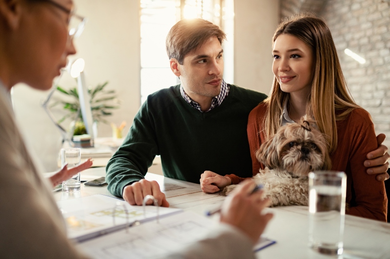 Young couple with dog meeting landlord to discuss rental agreement and security deposit deductions in California.
